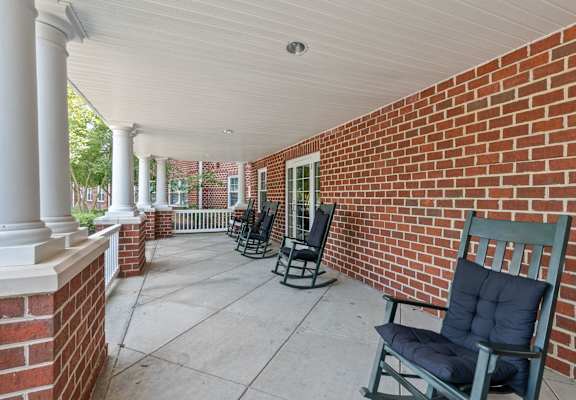 a covered patio with rocking chairs