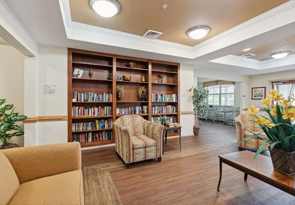 a seating area with couches and chairs and a bookshelf with books