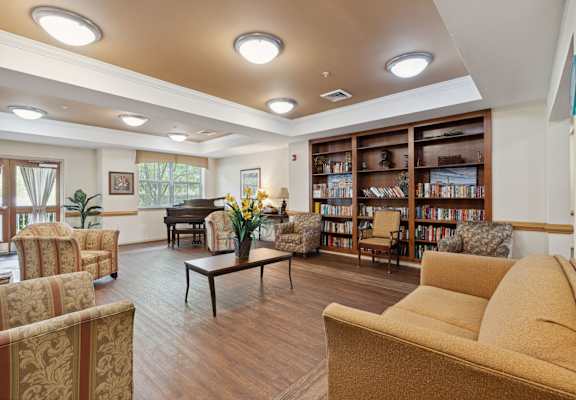 a room with couches chairs and a table with a vase of flowers and a piano