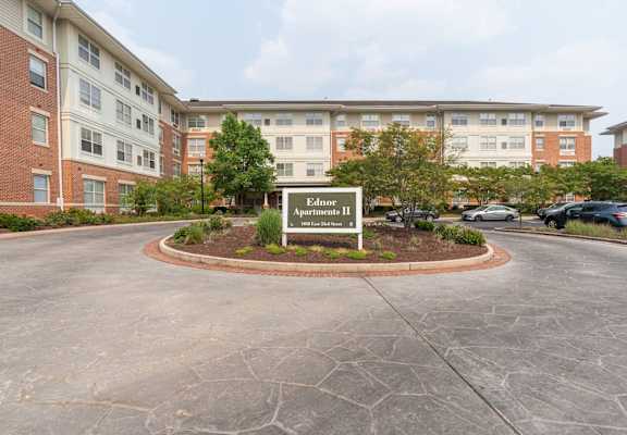 a circular driveway with a sign in the middle and a brick building in the background