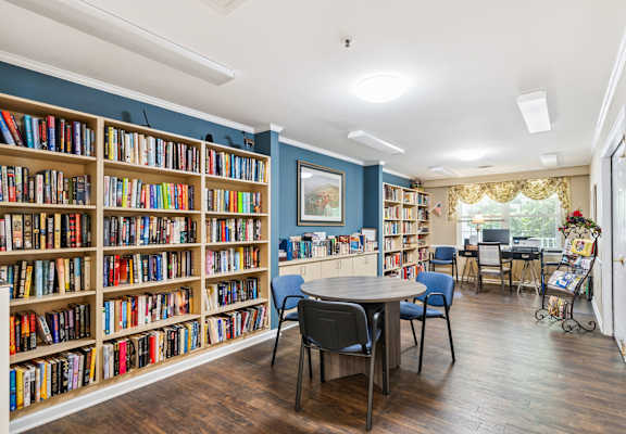 A room with a large bookshelf filled with books and a table with chairs.