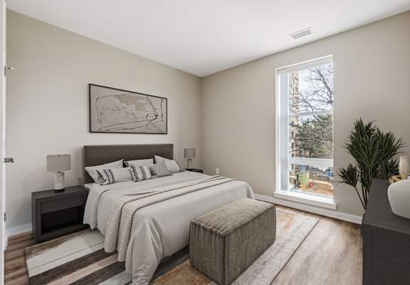 A bedroom with a large bed and a window overlooking a tree-lined street.