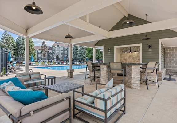 A covered patio with a pool in the background.