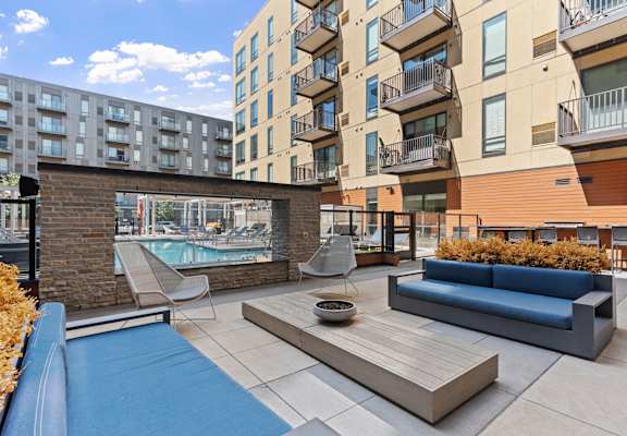 A modern outdoor seating area with a pool and a brick wall.