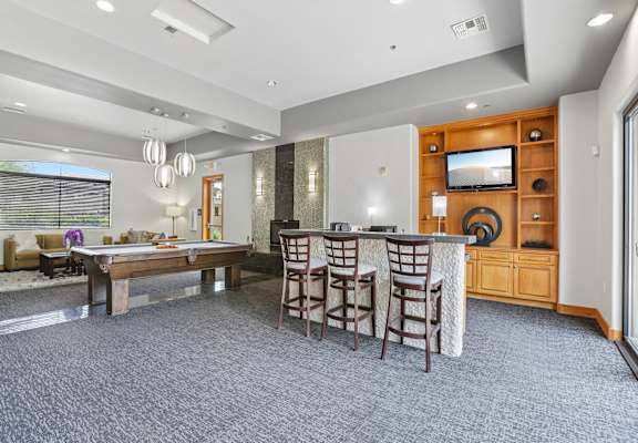 A spacious living room with a bar area and a television.