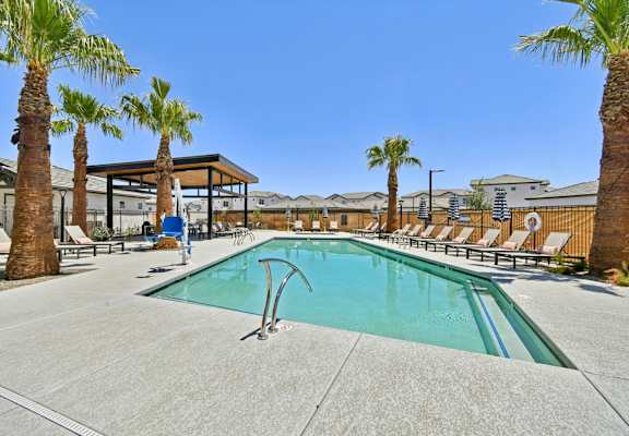 A pool surrounded by palm trees and lounge chairs.