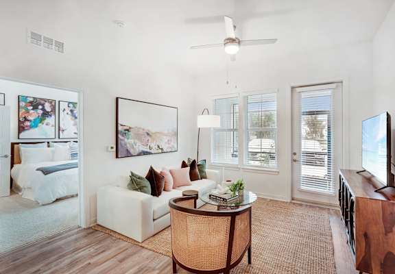 Open living room with wood floors, ceiling fan, and patio access.