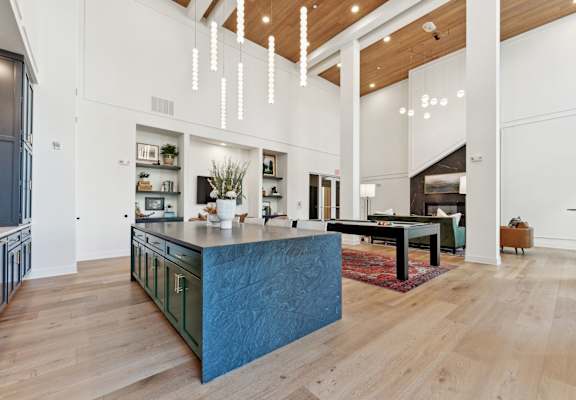 a large kitchen with a blue island and a living room with a pool table