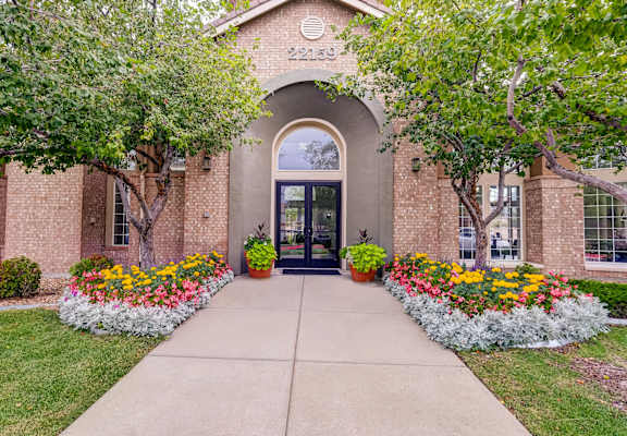 the front of a brick building with flowers and trees