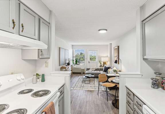 an open kitchen with white appliances and a living room with a couch