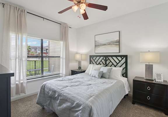 A bedroom with a bed, nightstands, and a ceiling fan.