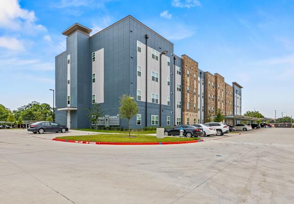 A parking lot in front of a multi-story building.