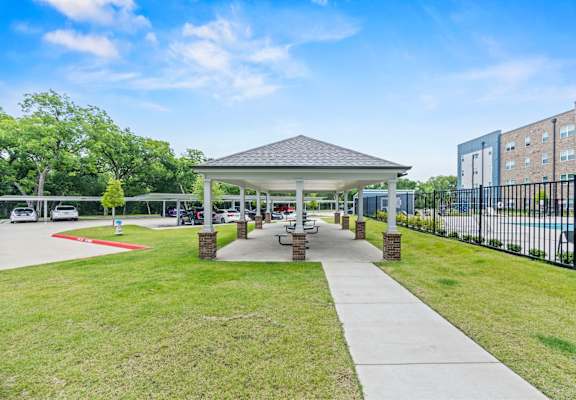 A covered walkway leads to a building with a white canopy and a red line on the ground.