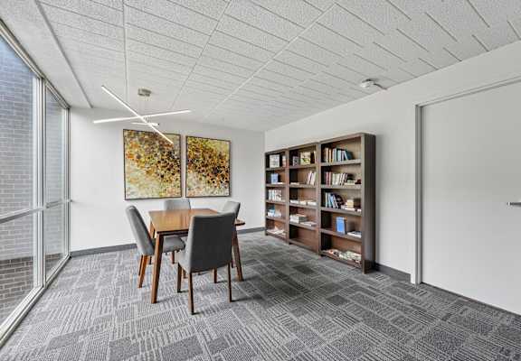 A room with a table, chairs, and a bookshelf.