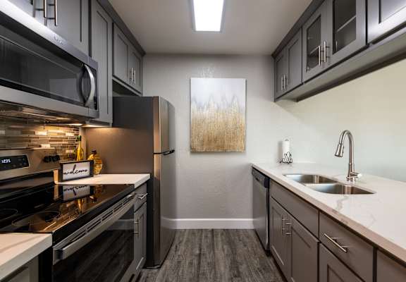 a kitchen with stainless steel appliances and white counter tops and a sink