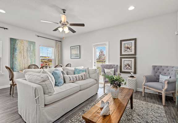 a living room with couches and chairs and a ceiling fan