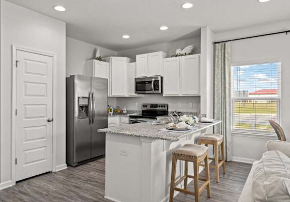 a kitchen with a island and stainless steel refrigerator