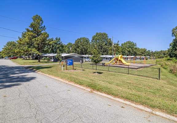 A playground with a yellow slide is located next to a road.