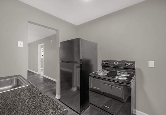 A black stove is in a kitchen with a refrigerator and a sink.