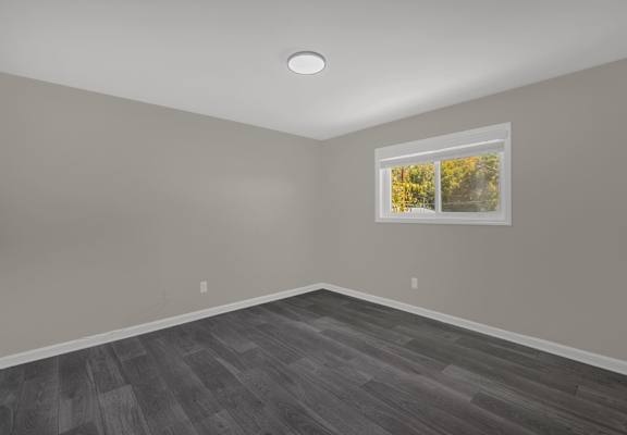 A room with a window showing trees outside.
