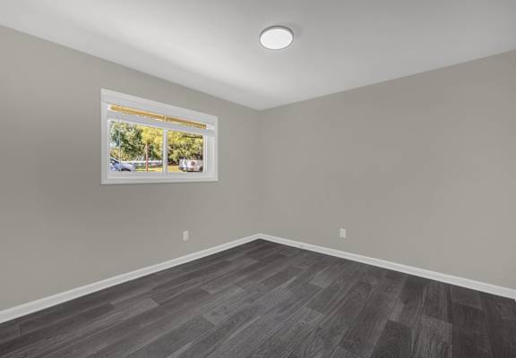 A room with a grey floor and a picture frame on the wall.