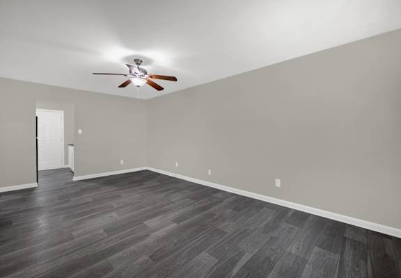 A room with a ceiling fan and wooden flooring.