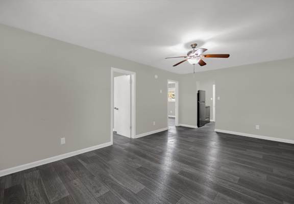 A room with a ceiling fan and wooden flooring.