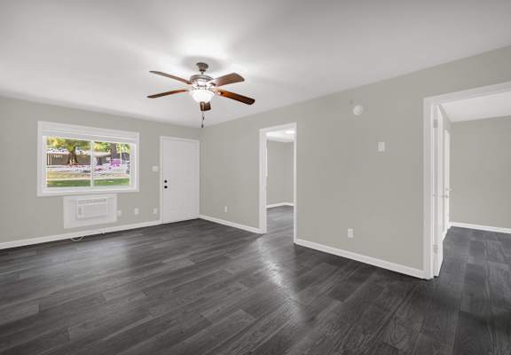 A room with a ceiling fan and a window overlooking a street.