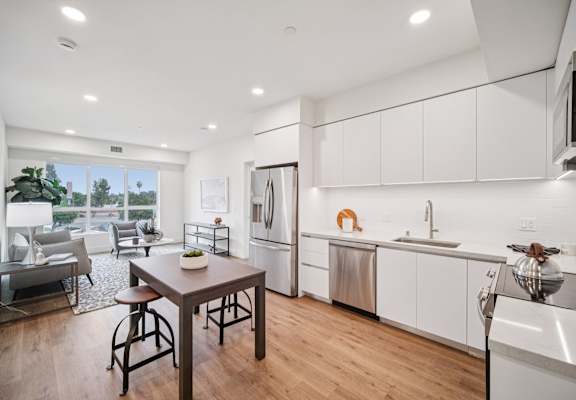 A modern kitchen with white cabinets and a wooden table.