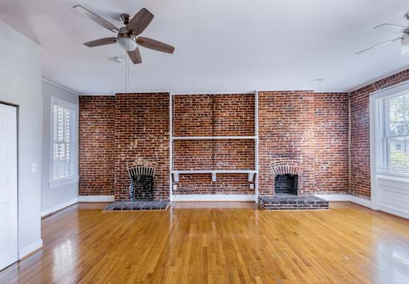 A room with a brick wall and a fireplace.