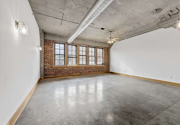 A large empty room with a brick wall and concrete floor.