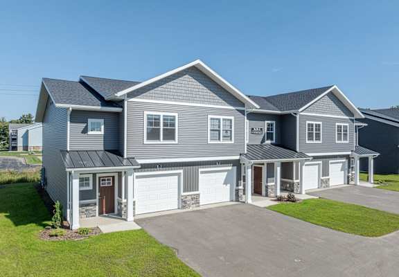 A large, modern house with a grey exterior and a spacious driveway.