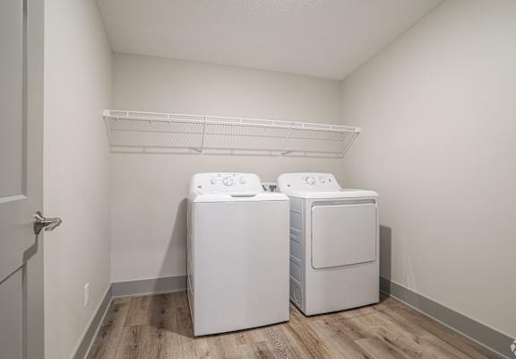 Two white front loading washing machines in a laundry room.