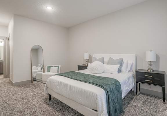 A bedroom with a large bed and a nightstand with a lamp.