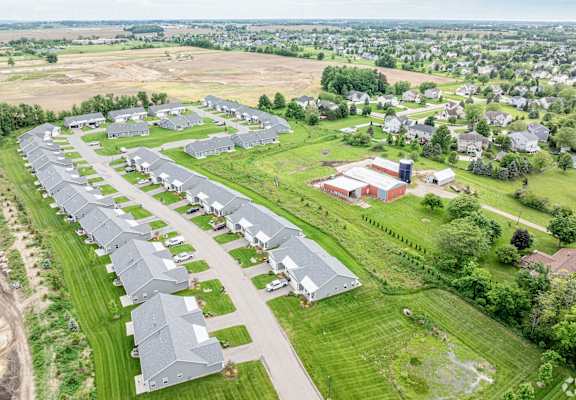 A large, modern building complex is situated in a green field.
