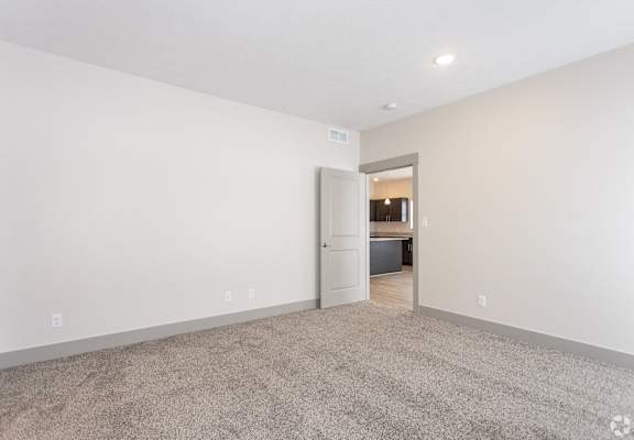 A room with a carpeted floor and a doorway leading to another room.