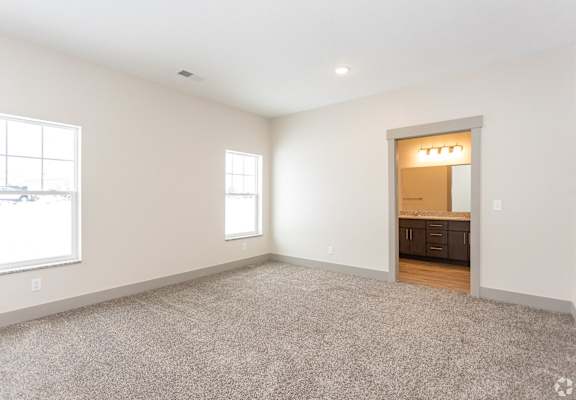 A spacious room with a carpeted floor and a doorway leading to another room.