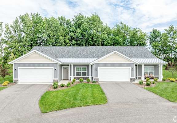 A two-car garage is attached to a house with a grey roof.