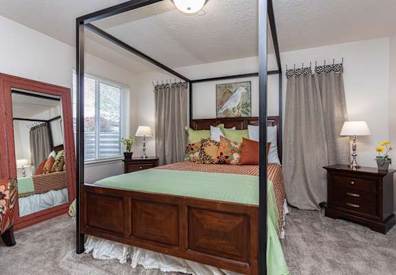 A bedroom with a four poster bed and a mirror.