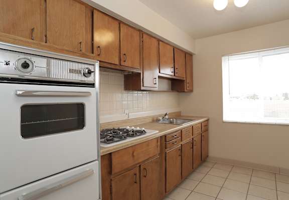 A kitchen with a white oven and wooden cabinets.