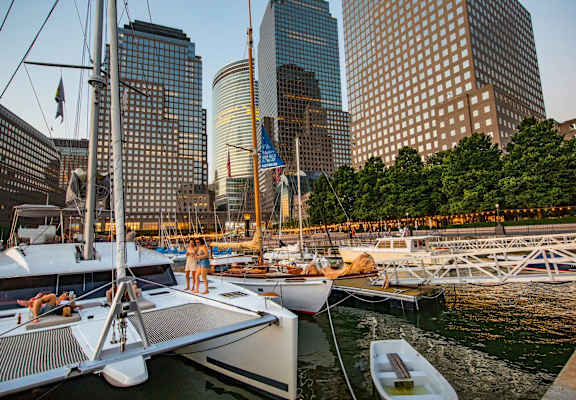 A yacht is docked at a marina with a city skyline in the background. at One West, New York, New York
