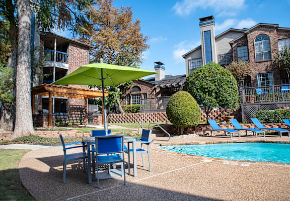 our apartments have a pool and patio with chairs and umbrella at Infinity on the Mark, Dallas, 75243