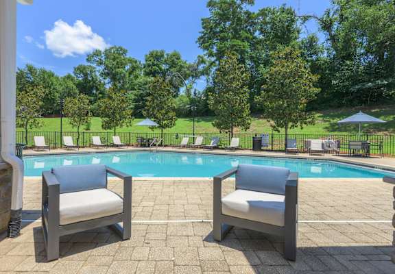 Two chairs are placed on a patio by a pool.