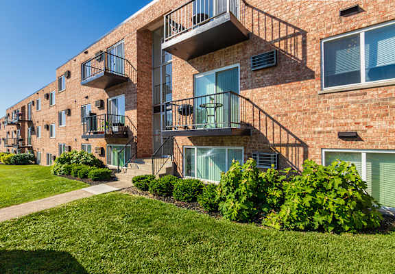 Brick apartment building with private balconies and landscaped walkway at Lisa Ridge Apartments