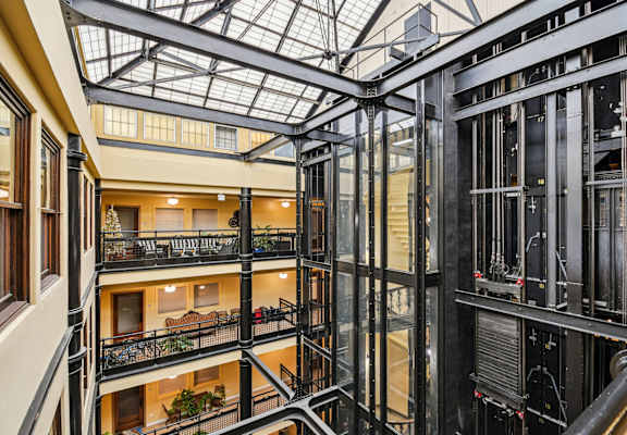 A view of a multi-level atrium with a glass ceiling and metal framing.