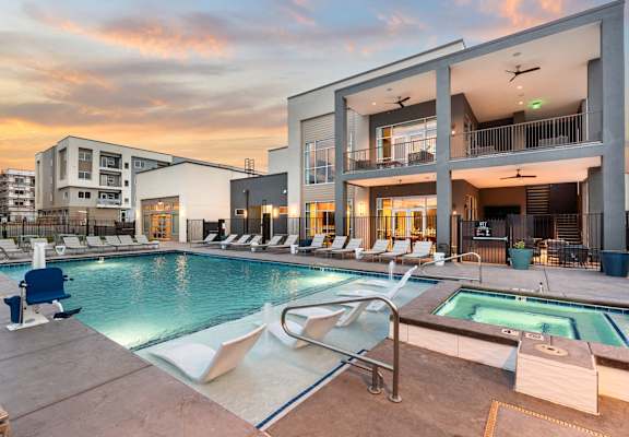 A modern building with a pool and lounge chairs.