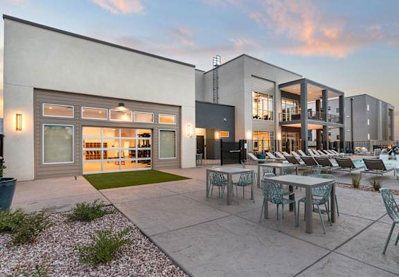 A modern building with a patio and chairs.