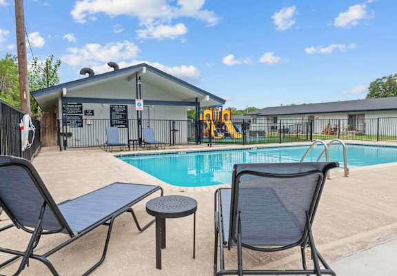 A pool with a slide and a building in the background.