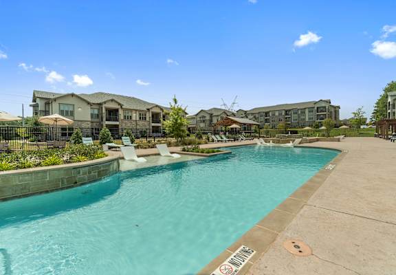 Resort-style swimming pool at Auberge of Tyler apartments in Tyler TX under blue sky.