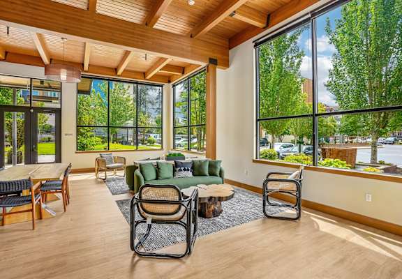 A living room with a couch, chairs, and a table with a view of the outdoors.